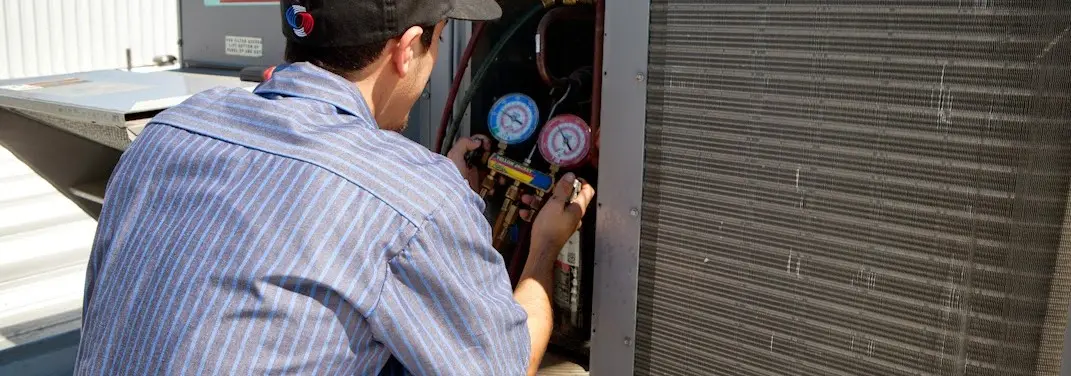 HVAC technician servicing a condenser unit in Swansea